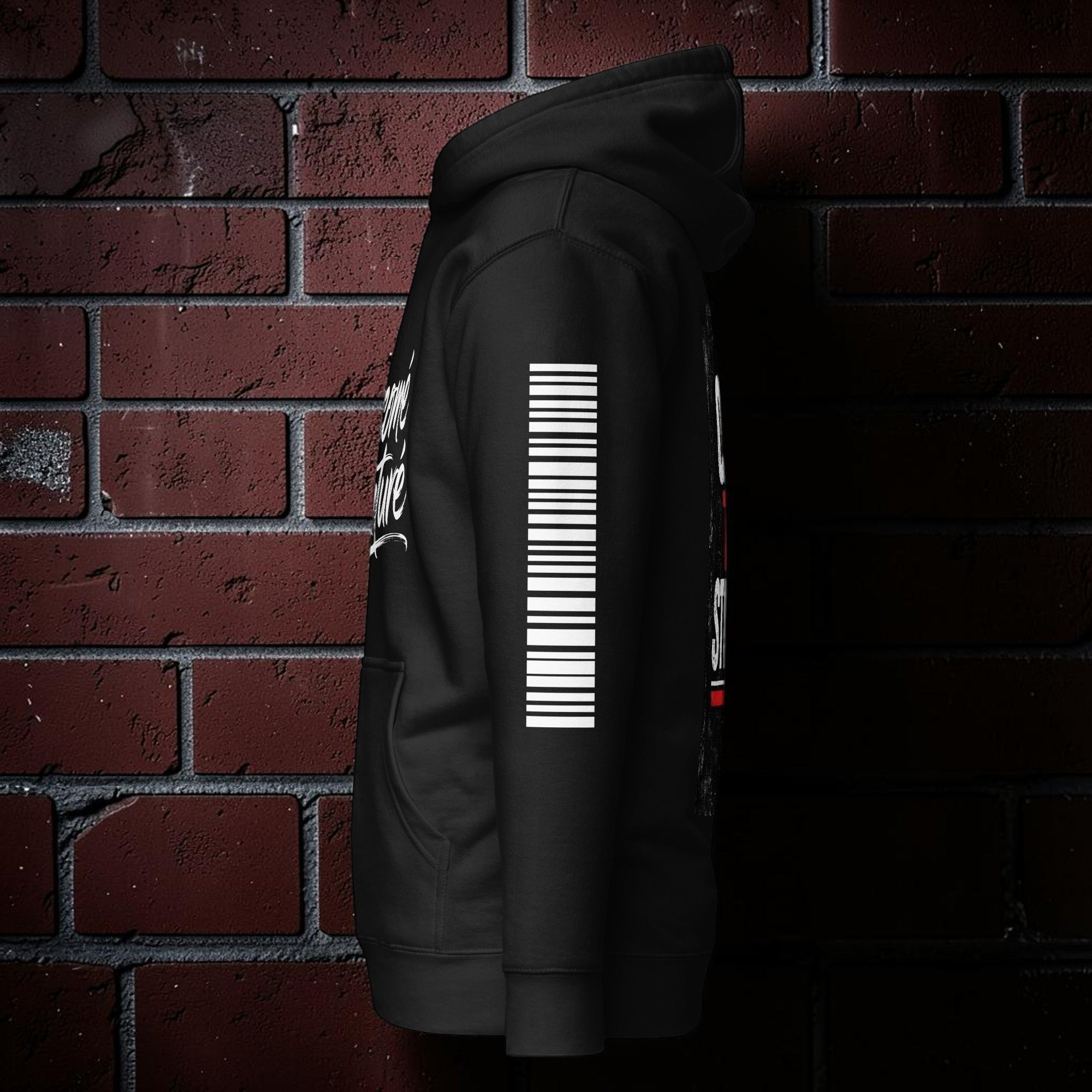 CocoMe Couture black premium hoodie with white sleeve graphic against a red brick wall background