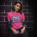 Woman wearing a pink CocoMe Couture crewneck t-shirt with a Street Luxury graffiti graphic print against a brick wall