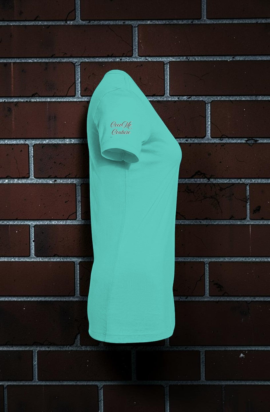 CocoMe Couture teal slim-fit women's graphic tee with side logo detail against a brick wall background